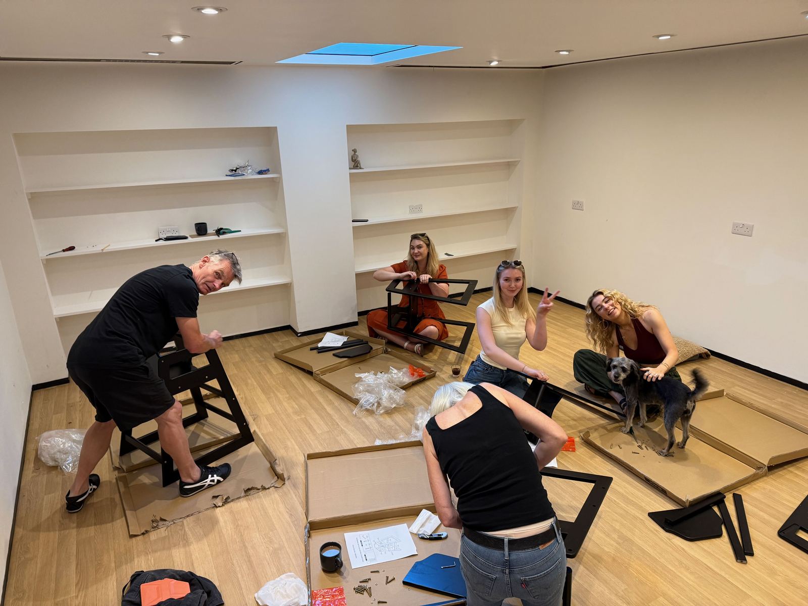 Friends assembling furniture in the studio, with the studio dog